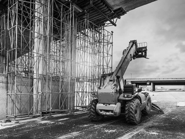 Construction forklift in action under bridge - black and white photo